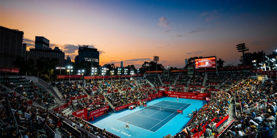 View of the courts at Victoria Park during the Hong Kong Tennis Open, illuminated by spotlights at dusk, as viewed from the upper-corner of the spectator stands.